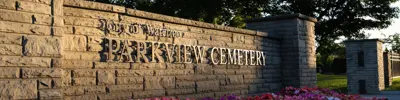 Image shows Parkview Cemetery entrance gate with a flowerbed below the sign